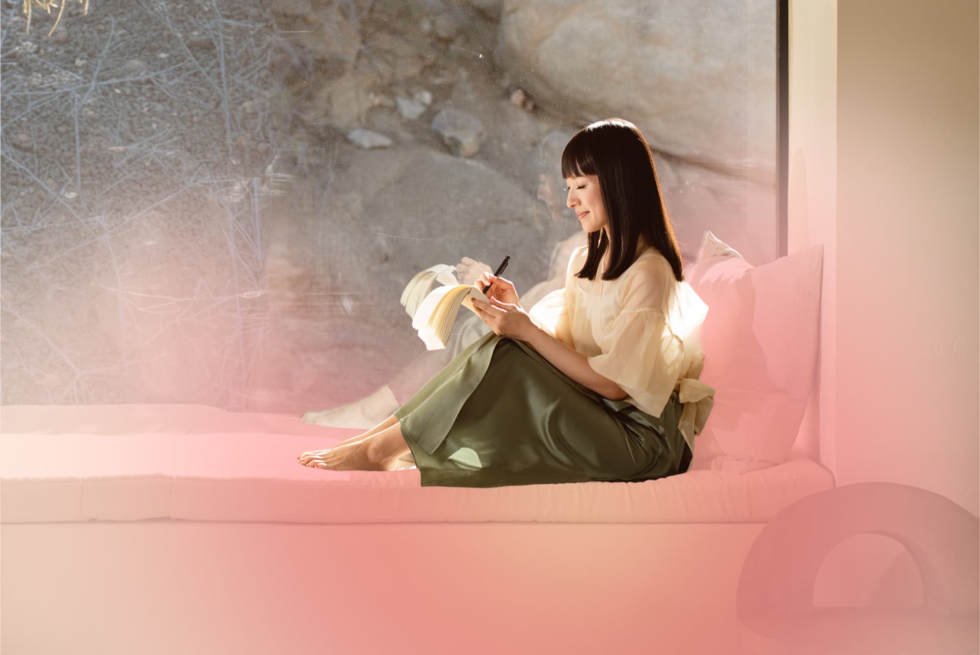 Writing in a notebook on a sunlit window seat with a soft pink glow